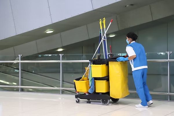 Hospital FM operative with cleaning equipment in modern corridor